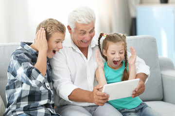 Fototapeta premium Grandfather and grandchildren with tablet on couch