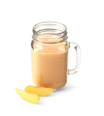 Mason jar with tasty smoothie and peach on light background