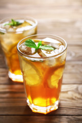 Glass of iced tea with lemon slices and mint on wooden background, closeup