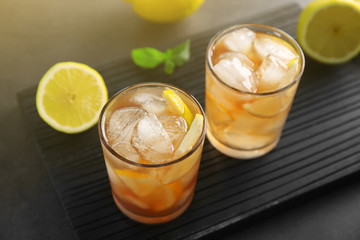 Glasses of iced tea with lemon slices on wooden cutting board
