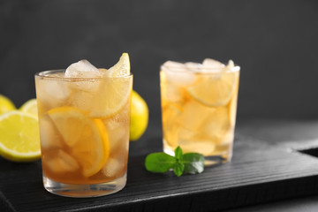 Glasses of iced tea with lemon slices on wooden cutting board