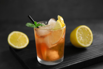 Glass of iced tea with lemon slices and mint on wooden cutting board