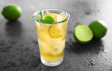Glass of iced tea with lime slices on gray background