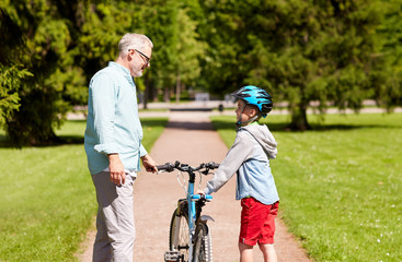 Obraz premium grandfather and boy with bicycle at summer park