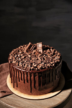Tasty chocolate cake on chair on dark background