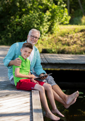 grandfather and boy with tablet pc on river berth