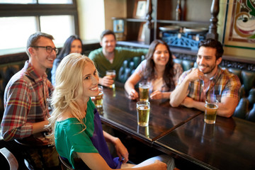 friends with beer watching football at bar or pub