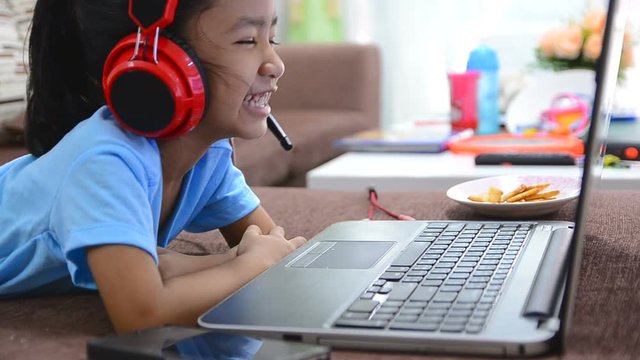 Close up shot of asian little girl using laptop computer at home with happiness
