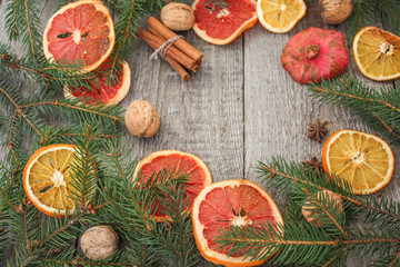 Christmas composition. Spruce branches, dried oranges, grapefruit, cinnamon, Christmas toys, walnuts, star anise, pomegranates on a wooden background.