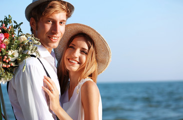 Young happy couple with flowers on seashore