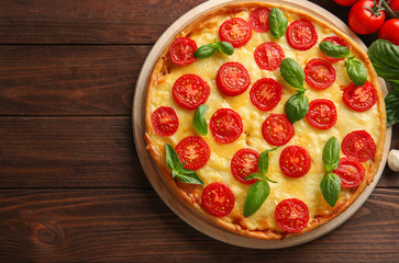 Fresh tasty pizza Margarita and tomatoes on wooden background, top view