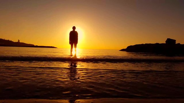 Woman on the seashore watching the sunset - 4K
