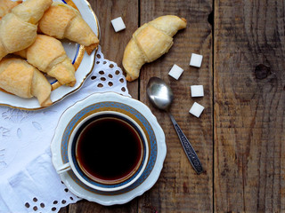 Breakfast with croissants and black coffee on wooden retro background.