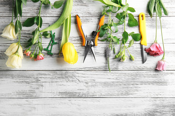 Beautiful flowers and florist equipment on grey wooden background