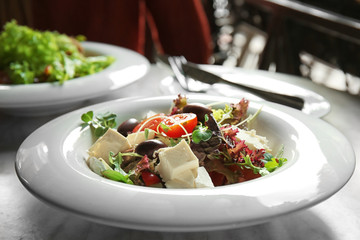 Tasty salad in white plate on table