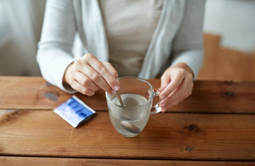 woman stirring medication in cup with spoon