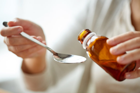 Woman Pouring Medication From Bottle To Spoon