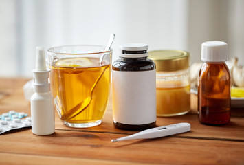 drugs, thermometer, honey and cup of tea on wood