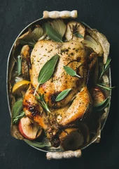  Oven roasted whole chicken with onion, apples and sage in metal serving tray over dark stone background, top view, selective focus, vertical composition. Celebration food concept © sonyakamoz