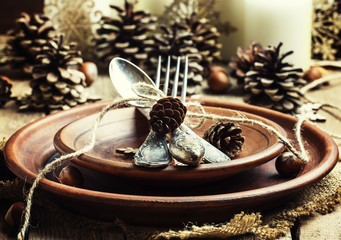 Table setting with pine cones, candles and snowflakes, pottery,