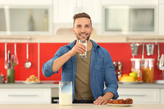 Young man drinking fresh milk at kitchen