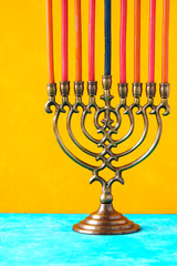 Fototapeta premium Hanukkah menorah with candles on the yellow background vertical