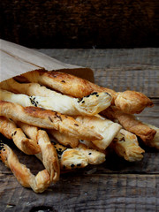 salty sticks of puff pastry sprinkled with cumin and Nigella on a wooden background