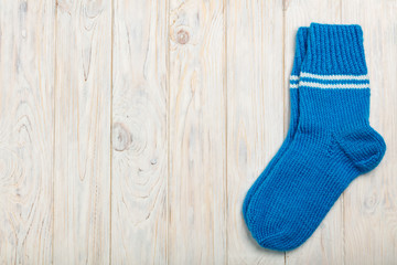 Knitted wool socks blue on light wooden background.