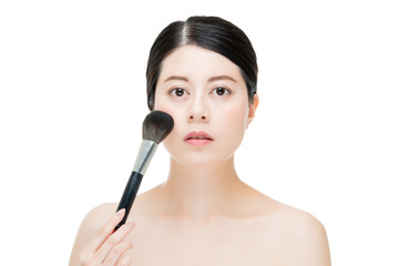 Obraz premium Beautiful young woman applying foundation powder blush with make