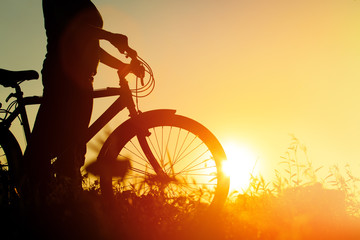 Fototapeta na wymiar silhouette of young woman riding bike at sunset