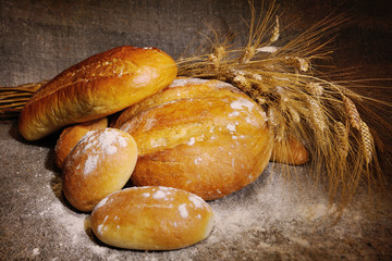 freshly baked bread, loaf, buns sprinkled with flour wheat ears on sacking