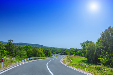 Beautiful asphalt freeway, motorway, highway without traffic through of southern landscape mountains forest during summer on a sunny day. Travel road concept.
