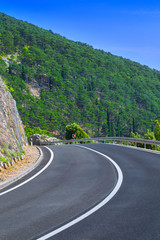 Beautiful asphalt freeway, motorway, highway without traffic through of southern landscape mountains forest during summer on a sunny day. Travel road concept.