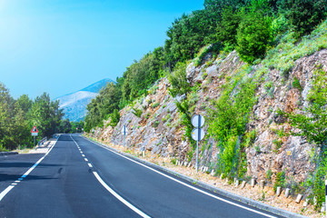 Beautiful asphalt freeway, motorway, highway without traffic through of southern landscape mountains forest during summer on a sunny day. Travel road concept.