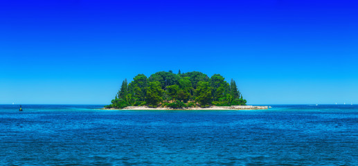 a small green island in the calm sea in warm summer day