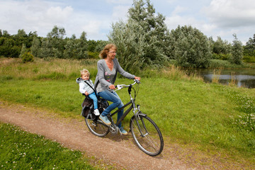 Obraz premium Happy grandmother with grandchild cycling towards you in nature