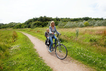 Fototapeta premium Happy woman on a bike with child behind bicycle