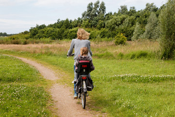 Woman and child cycling away from you in nature