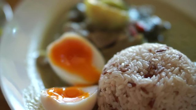 Green curry over rice with half boiled egg, local style Thai street food