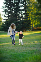 Mom and little son running in the Park on the grass, holding hands, full length.