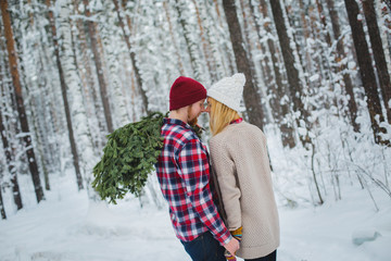 young couple with fir twigs walk in the winter woods