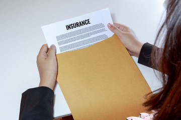 Woman hands holding and looking at Insurance document in envelop