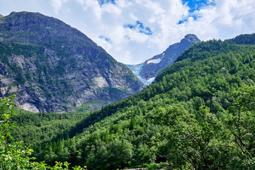 Fototapeta na wymiar Folgefonna Glacier seen from the west side at Bondhussoen with green tree covered slopes in the foreground