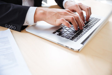 Hands of young businessman using laptop at the table