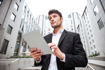 Businessman standing and using tablet near business center