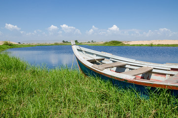 Fishing boat anchored in lagoon with green grass and dunes