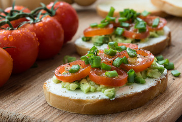Cooking bruschetta with cream cheese, avocado and chopped tomatoes