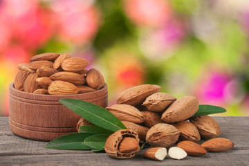 almonds in a bowl on the old wooden board with blurred garden background