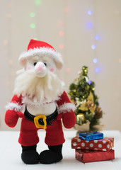 Knitted toy Santa Claus on a background of colorful bokeh.