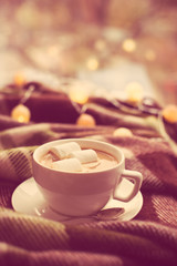 cup of coffee with marshmallows, warm blanket and Christmas ligh